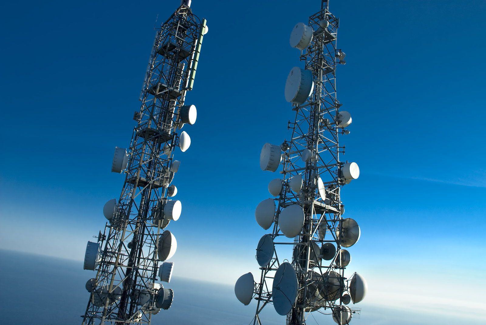 Two lattice telecom towers carrying microwave dishes and antennas